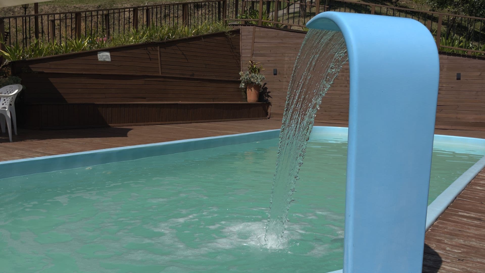Piscina aquecida com cascata, cercada pelo deck de madeira